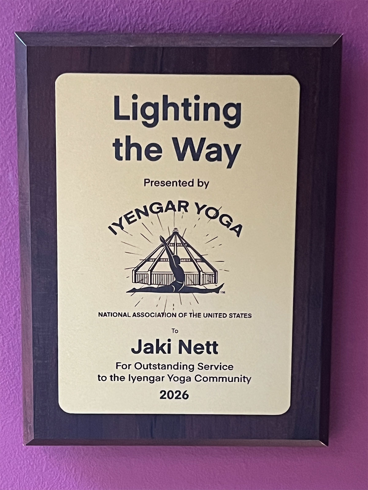 Lighting the Way award plaque presented to Jaki Nett by the Iyengar Yoga National Association of the United States for Outstanding Service to the Iyengar Yoga Community, 2026.